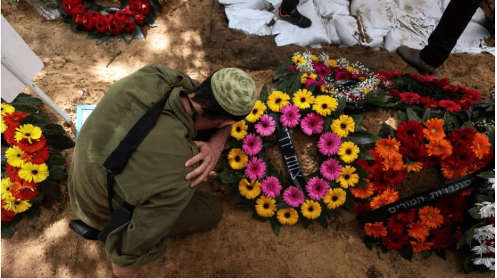Un soldat israélien se recueille sur la tombe d'un confrère tué dans l'attaque du samedi 7 octobre. Photo: Ronen Zvulun/Reuters