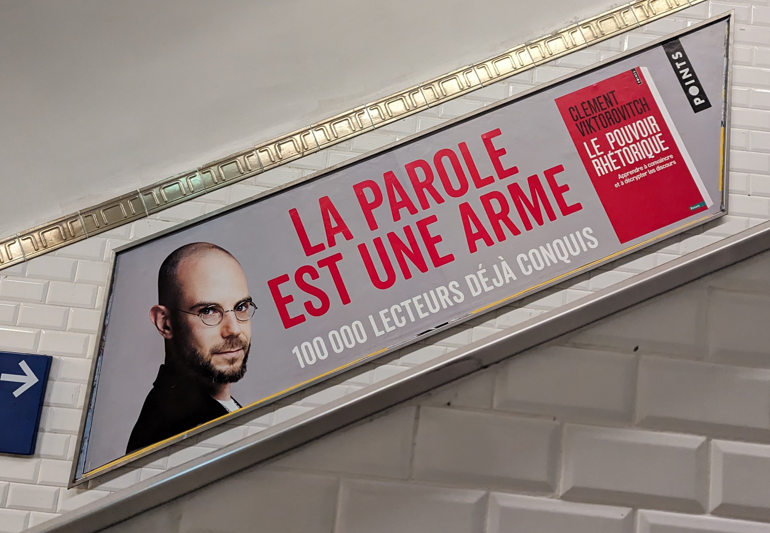 Photo prise dans le métro d'une affiche de promotion du livre "Le pouvoir rhétorique" de Clément Viktorovitch où il est écrit "La parole est une arme"