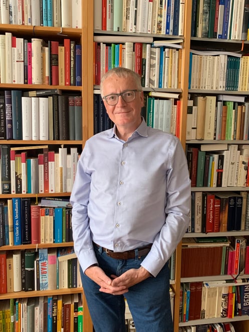 Stephan Steinlein devant sa bibliothèque dans son appartement berlinois qui compte de nombreux ouvrages de théologie