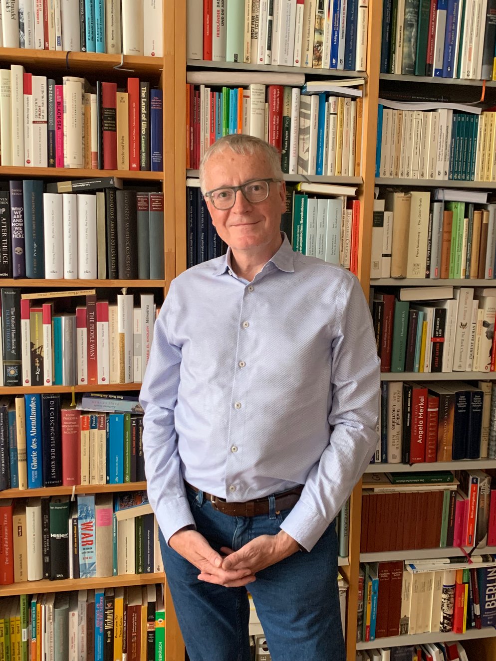 Stephan Steinlein devant sa bibliothèque dans son appartement berlinois qui compte de nombreux ouvrages de théologie