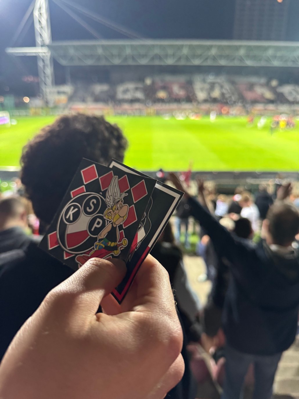 Un fan ou kibic du Polonia Warszawa tient un sticker. ©Kilian Bigogne