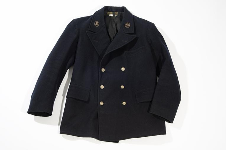 Veste Cheminote croisée en drap de laine bleu, doublée d’un satin noir, ornée de 2 rangées de 3 boutons dorés, sigle brodé au point de cannetille avec un fil métallique doré de chaque côté du col. Crédits : Musée de la ville Saint-Quentin-en-Yvelines/ E. Deschamps
