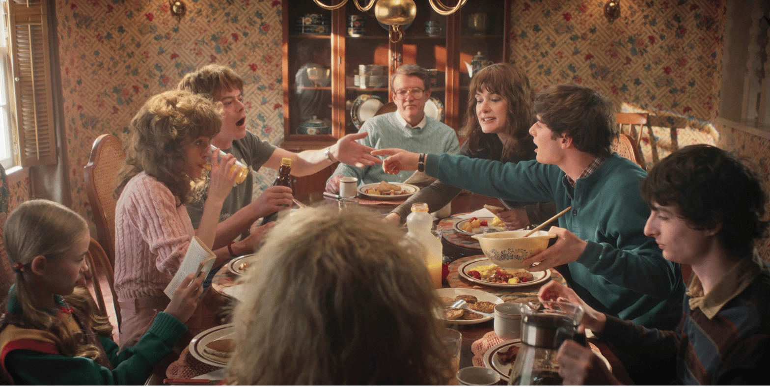 On peut voir dans cette photo une scène qui se déroule très probablement dans l’épisode 1, plus exactement au timecode de 6:27. On y voit ce qui semble être un petit déjeuner paisible entre les familles Byers et Wheeler, qui donc semblent (est-ce le cas?) vivre sous le même toit depuis la fin de la saison 4.